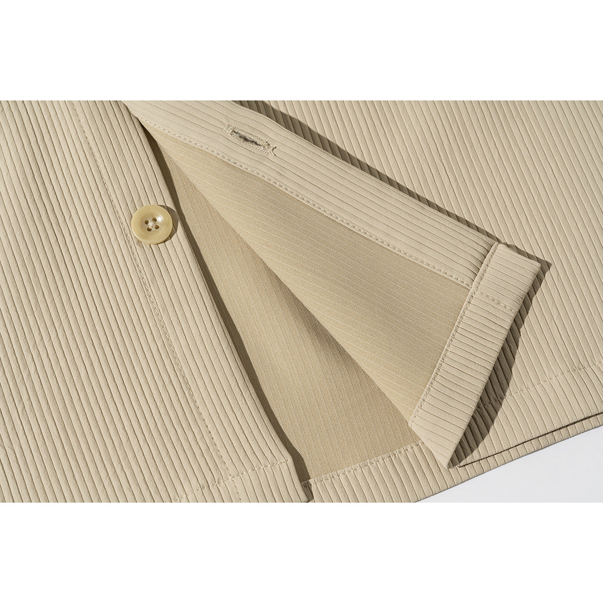 Close-up of a beige ribbed shirt's button and open front placket.