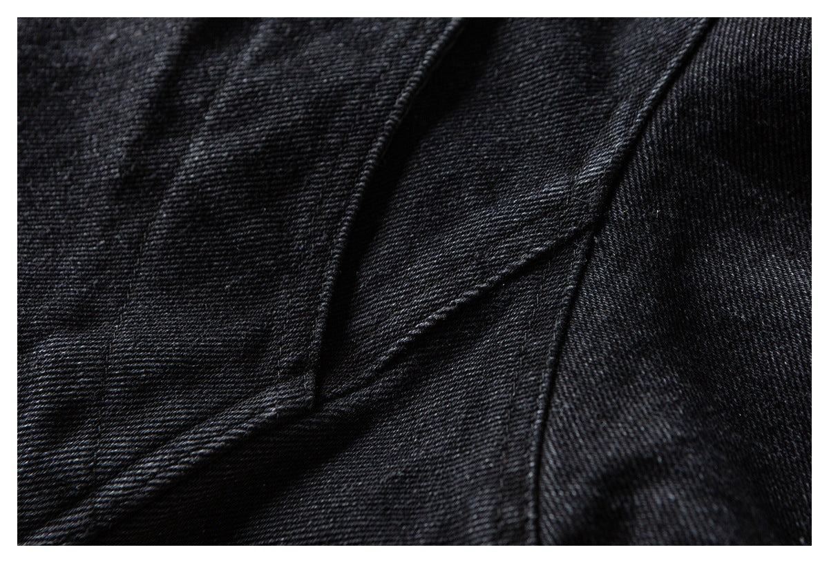 Close-up of black fabric showing diagonal stitched seams and overlapping folds.