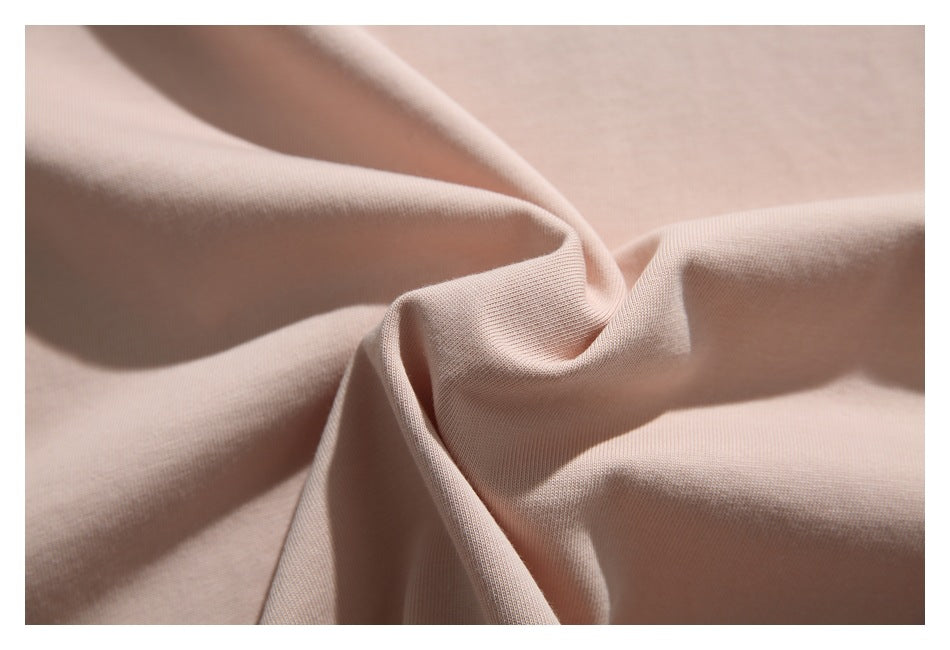 Close-up of light blush-pink fabric draped into soft folds, showing its surface texture.