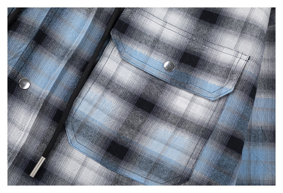 Close-up of a gray, black, and blue plaid shirt pocket with a metal snap and black drawcord.