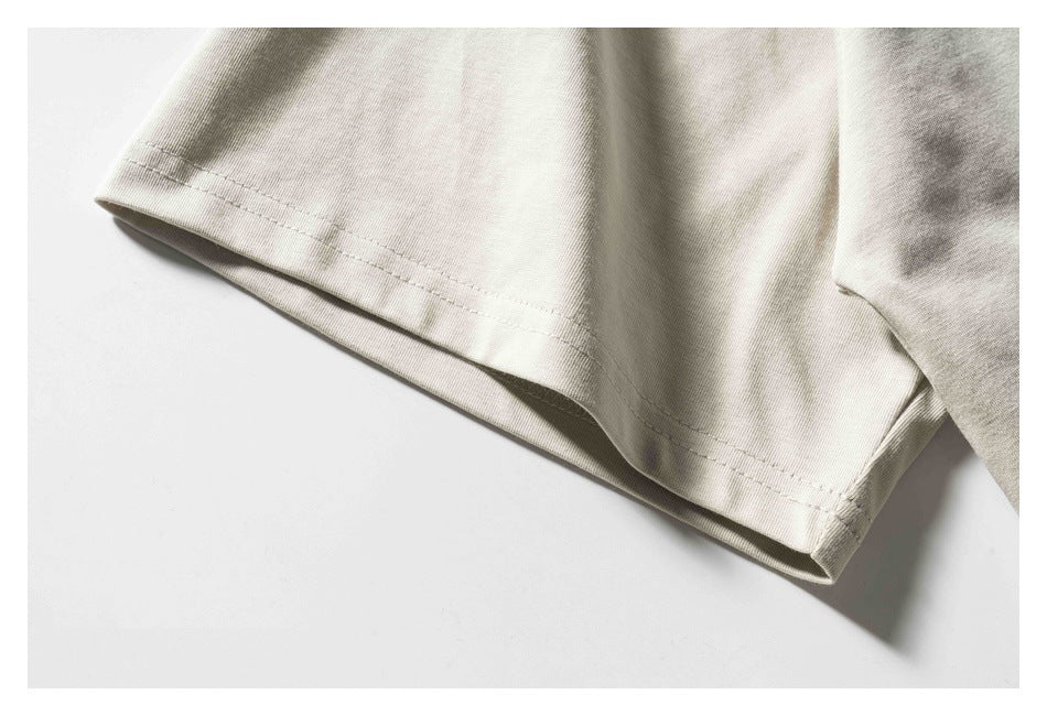 Close-up of the double-stitched sleeve hem on a light beige T-shirt.