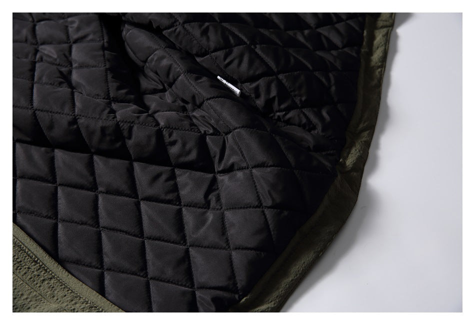 Close-up of black square-quilted garment lining with dark olive-green edging and a small white tag.