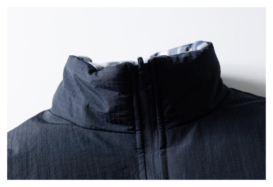 Close-up of a dark jacket’s high collar and central zipper, showing subtle stitched texture.