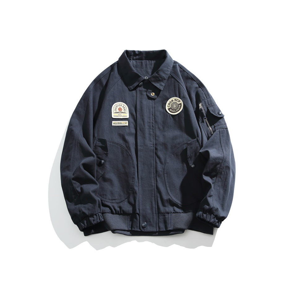 Navy bomber-style jacket with fold-down collar, chest patches, curved front pockets and sleeve zip pocket