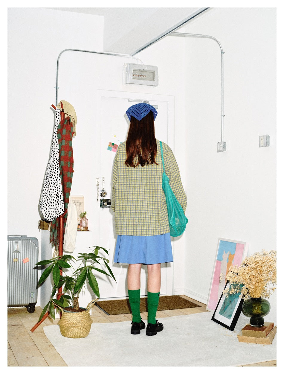 Back view of a model wearing the yellow and blue check shirt with a blue skirt and green tote bag
