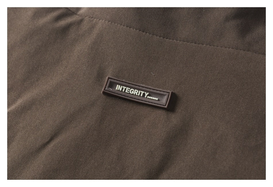 Close-up of a dark brown garment with a raised rectangular patch reading “INTEGRITY.”