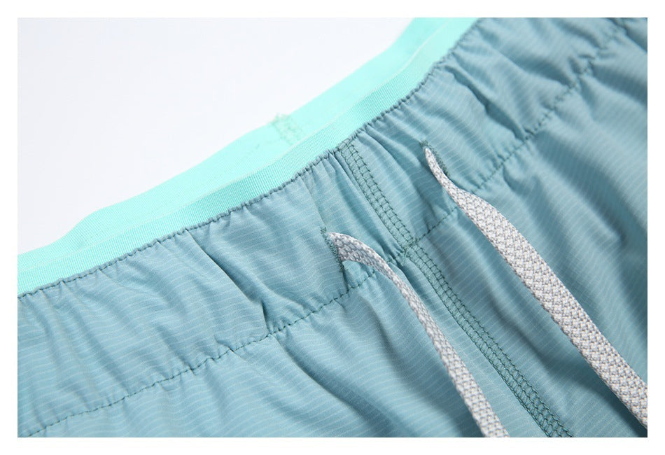 Close-up of blue shorts with an elastic waistband and two white drawcords.