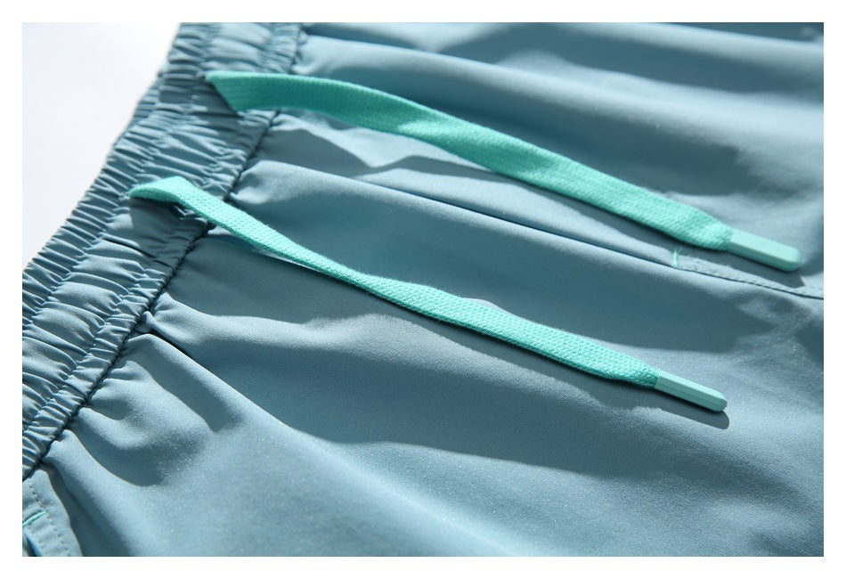 Close-up of light blue shorts with two turquoise drawstrings at the elastic waistband.