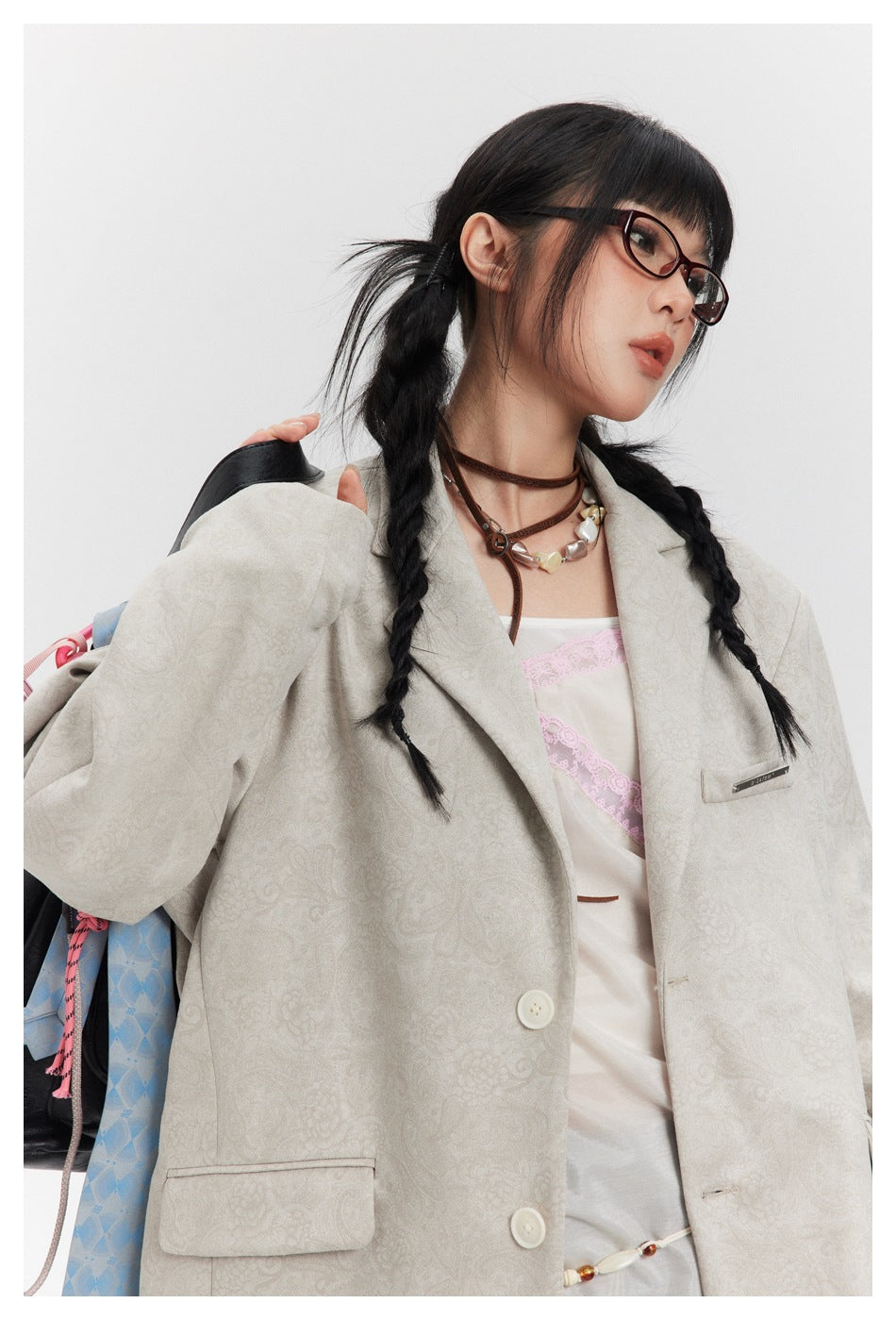 Close view of a model wearing a light beige patterned blazer with pale buttons and a chest pocket.