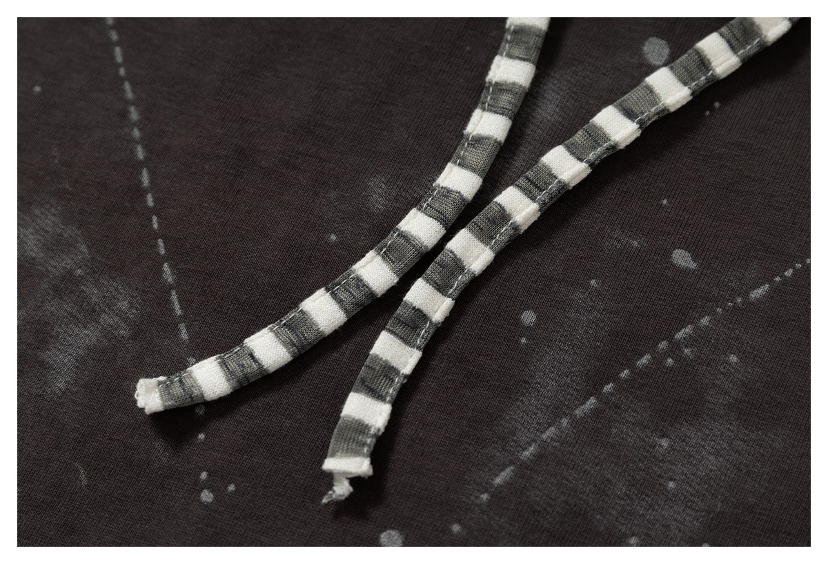 Close-up of two gray-and-off-white striped drawstrings against dark fabric with pale scattered markings.