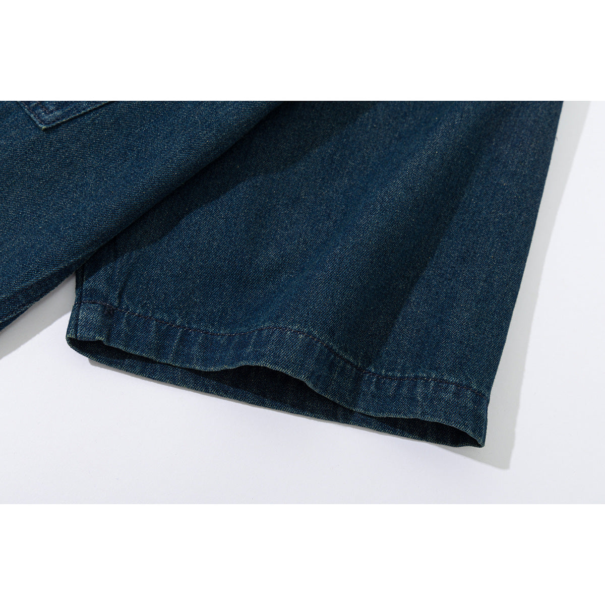 Close-up of the dark indigo denim shirt's sleeve cuff and stitched hem.