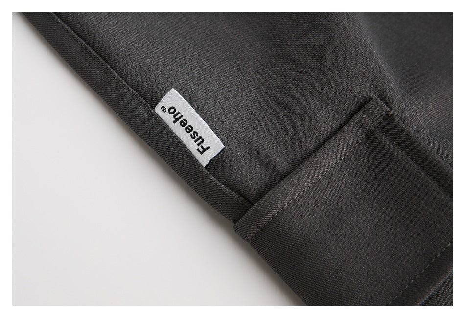 Close-up of a charcoal garment seam and folded edge, with a small sewn-in text label.