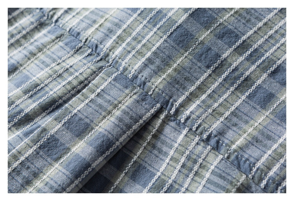 Close-up of blue-gray plaid fabric showing stitched seams and gathered folds.