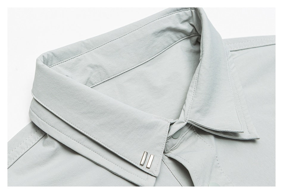 Close-up of the pale gray-green shirt's pointed collar, placket, stitching, and small metal collar detail.