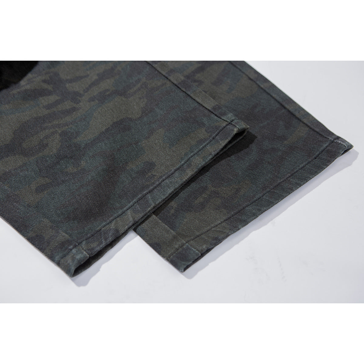 Close-up of the stitched hem on dark charcoal camouflage pants.