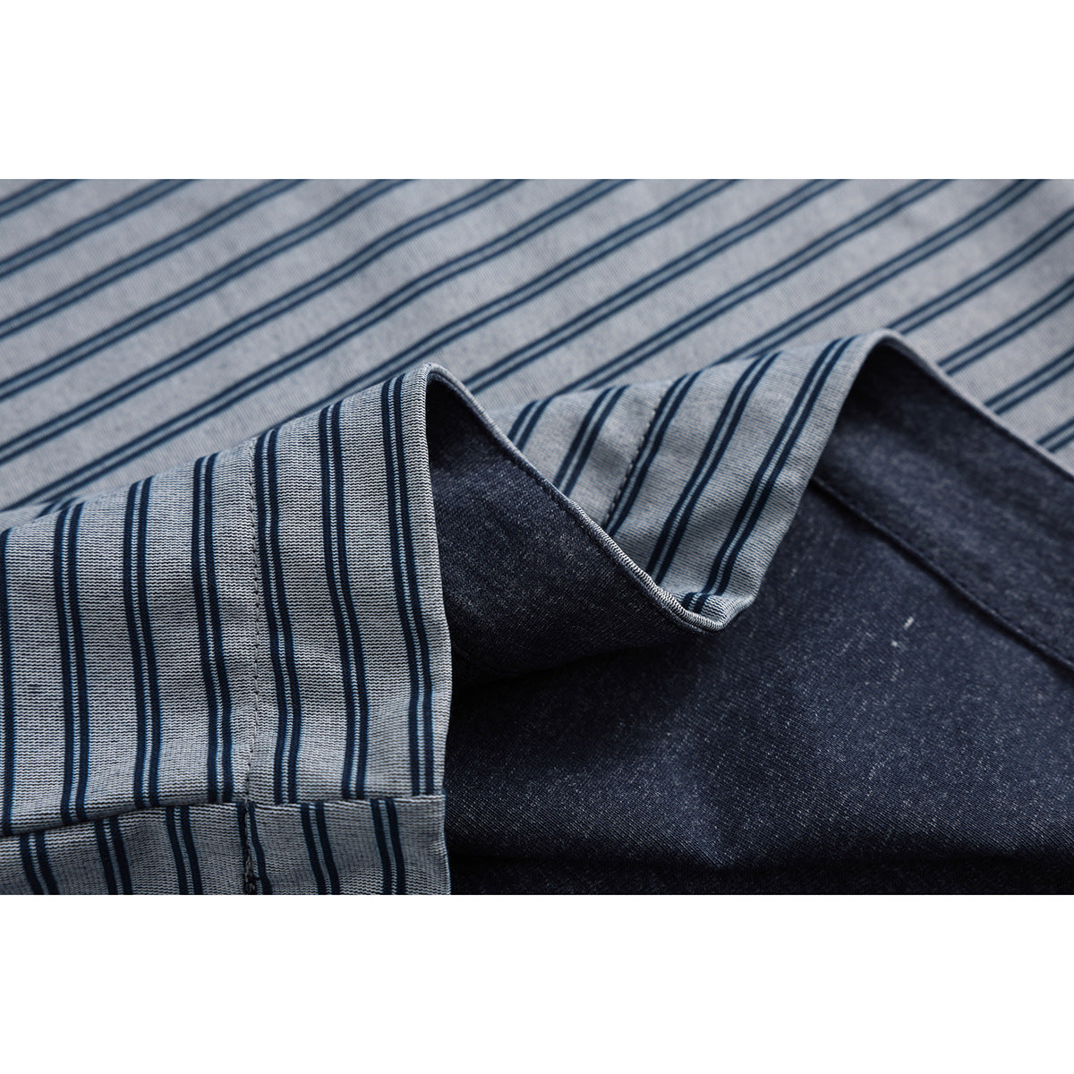 Close-up of blue-gray striped shirt fabric folded to show its dark reverse side.