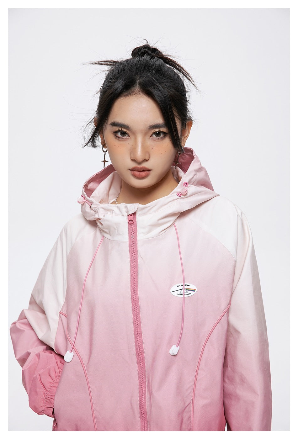 Close front view of a model wearing a pale pink hooded zip jacket with pink drawcords and elastic cuffs.