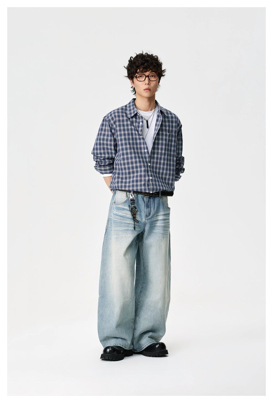 Full-length model wearing a navy plaid shirt, white tee, and very wide light-wash jeans.