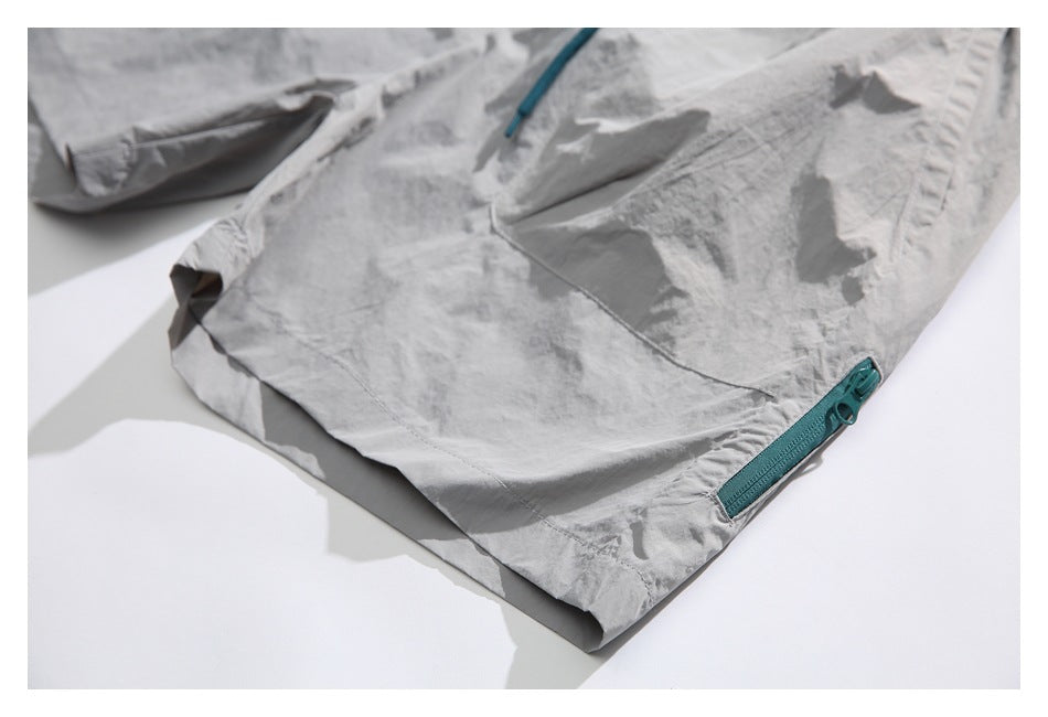 Close-up of a light gray shorts leg with a teal zipper near the hem.