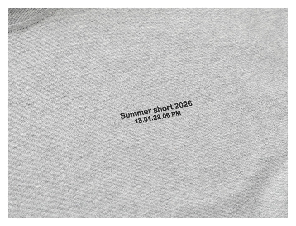 Close-up of the gray shirt's small black chest text print on the fabric.