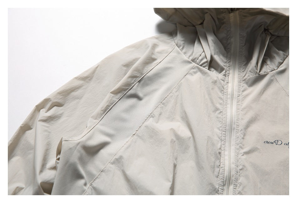 Close-up of the light beige jacket's front zipper, shoulder panel, and small chest print.