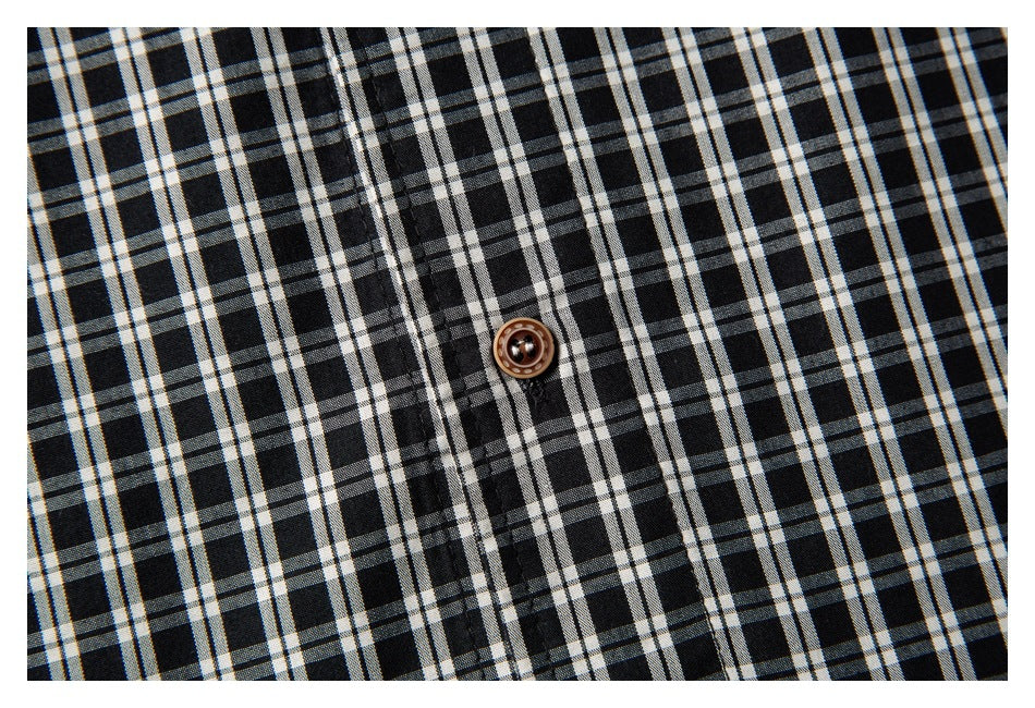 Close-up of a brown button on black-and-white plaid shirt fabric.