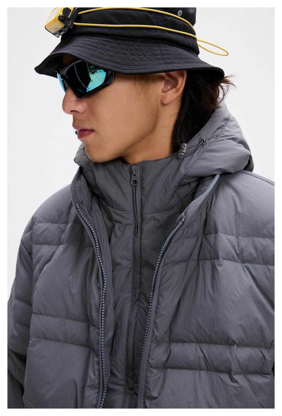 Close-up of a gray quilted jacket's hood, high collar, and layered front zippers.