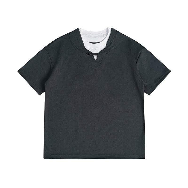 Dark charcoal short-sleeve faux two-piece T-shirt with white under-layer at the neckline and small black button, flat lay