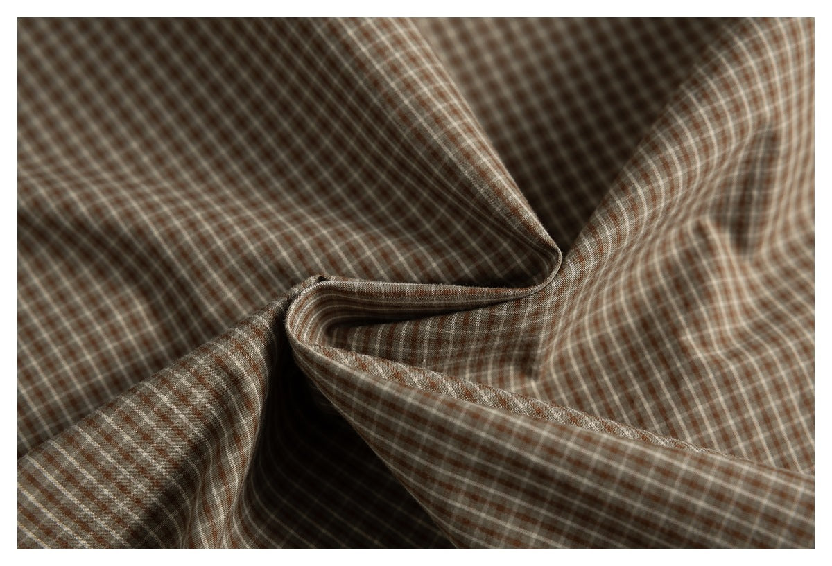 Close-up of brown and cream checked shirt fabric draped into soft folds.