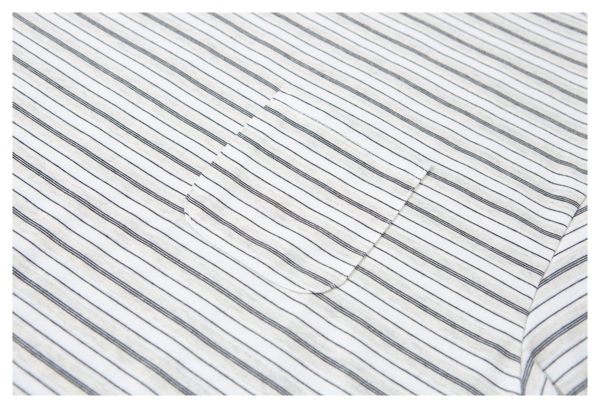 Close-up of a patch pocket on an ivory shirt with thin dark stripes.