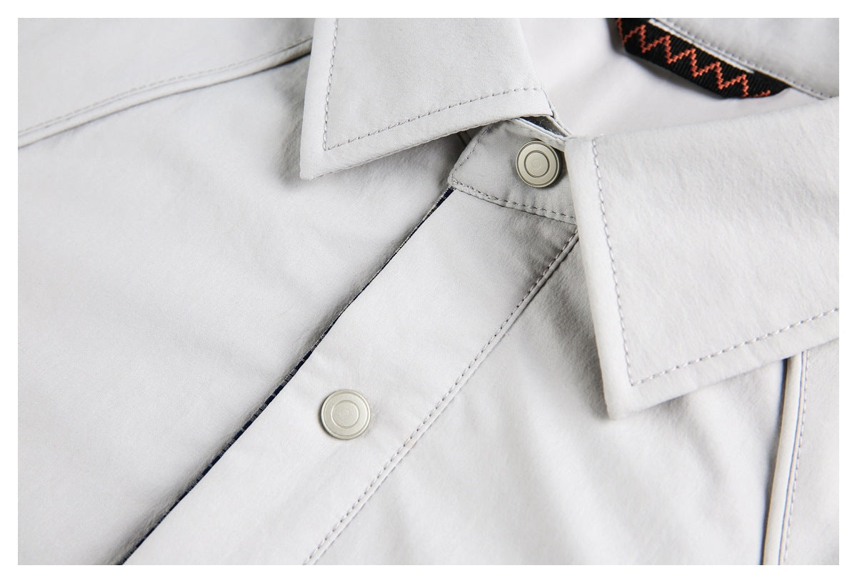 Close-up of the light gray jacket's collar, two round snaps, and stitched front placket.