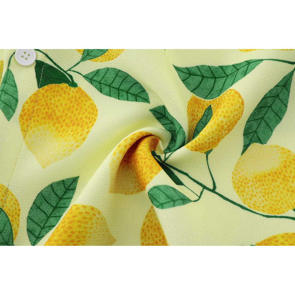 Close-up of pale yellow fabric printed with yellow lemons and green leaves, gathered beside a white button.