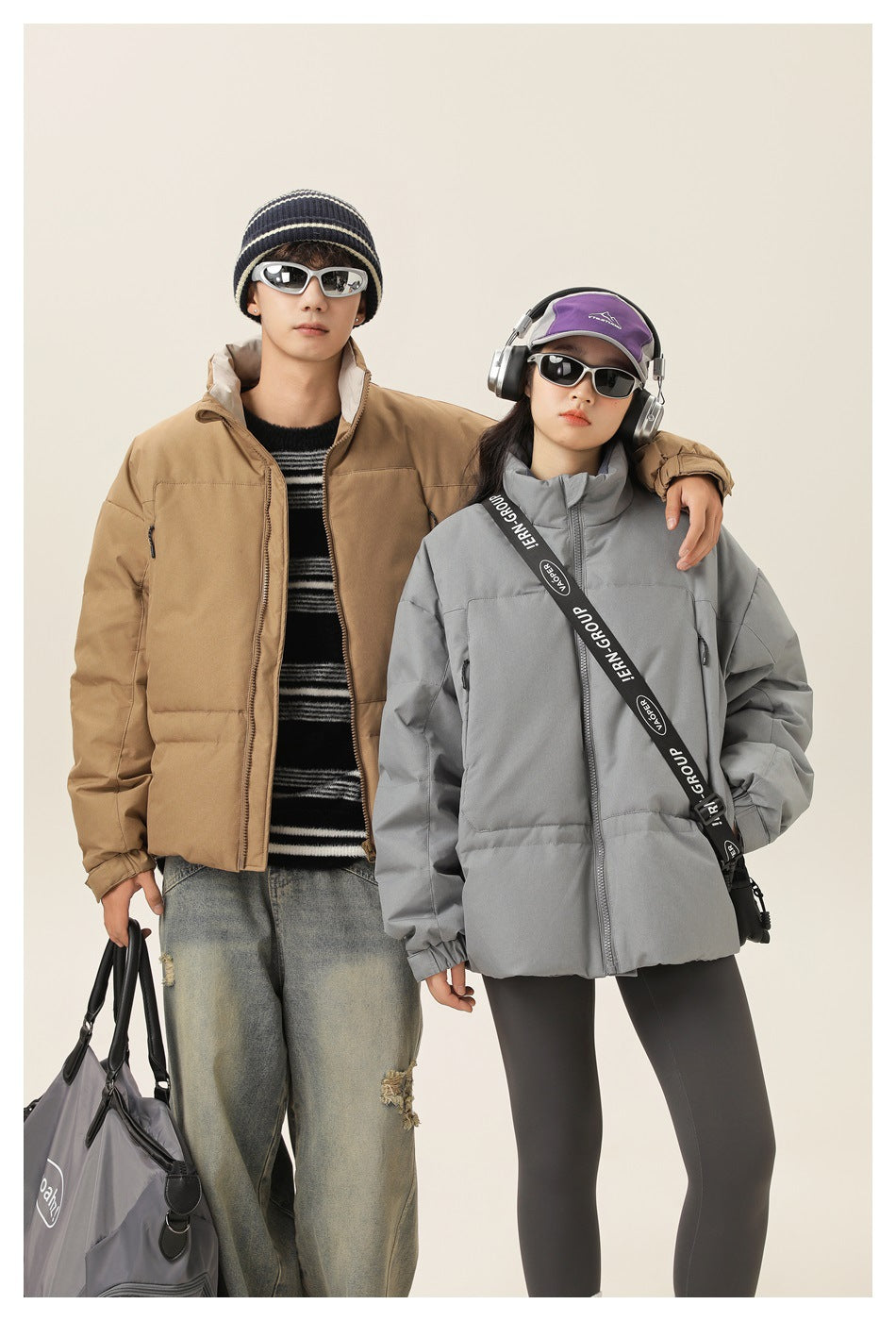 Two models pose in tan and light-gray zip-front puffer jackets with high collars and roomy pockets.