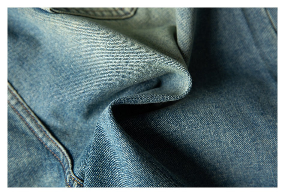 Close-up of blue denim fabric folded to show its woven texture and stitching.
