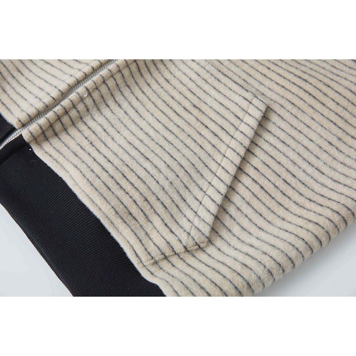 Close-up of the beige jacket's gray stripes, angled seam, and black ribbed trim.