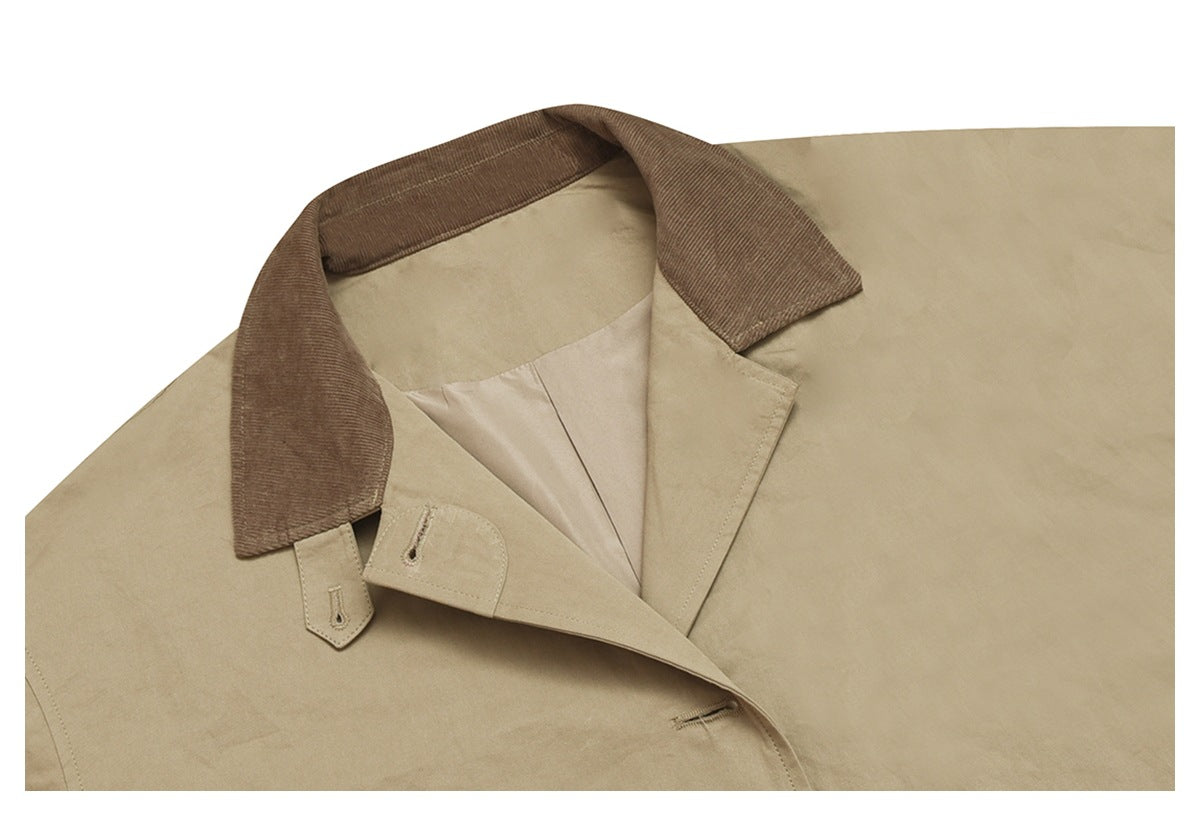 Close-up of a beige coat's wide brown corduroy collar, lapels, button tabs, and pale lining.