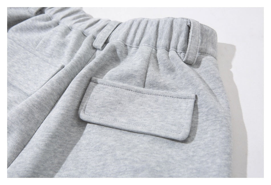 Close-up of light gray heathered pants with a gathered waistband, belt loops, and a flap pocket.
