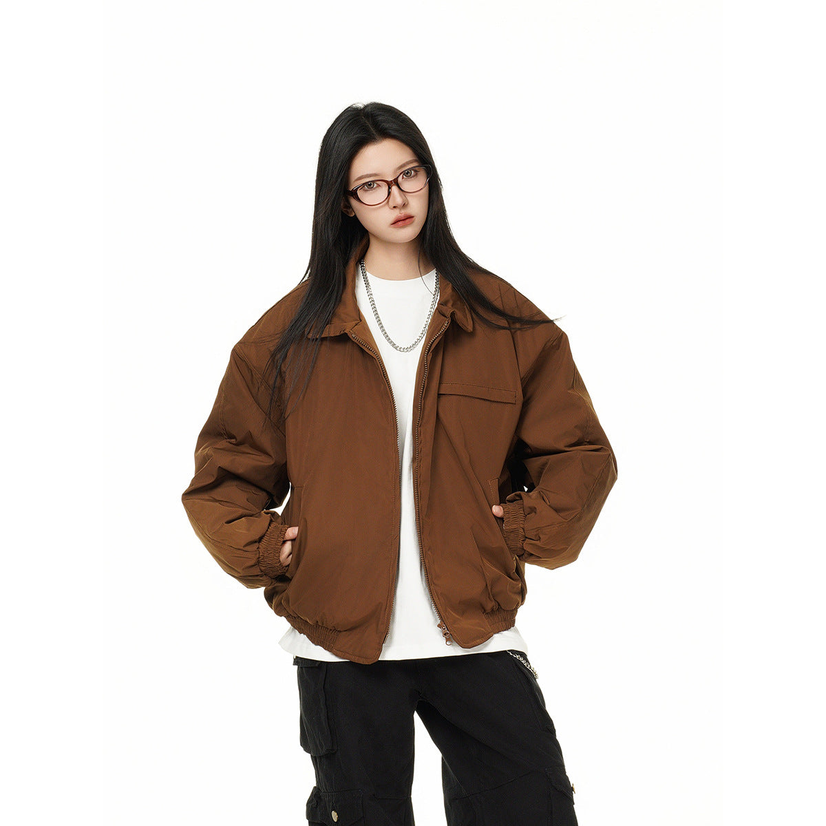 Model wearing an open brown oversized jacket with a collar, chest pocket, gathered cuffs and hem, and front zipper.