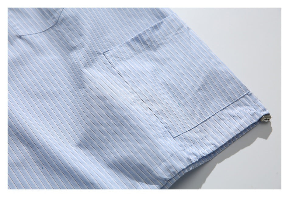 Close-up of a light blue pinstriped shirt pocket and hem laid flat.