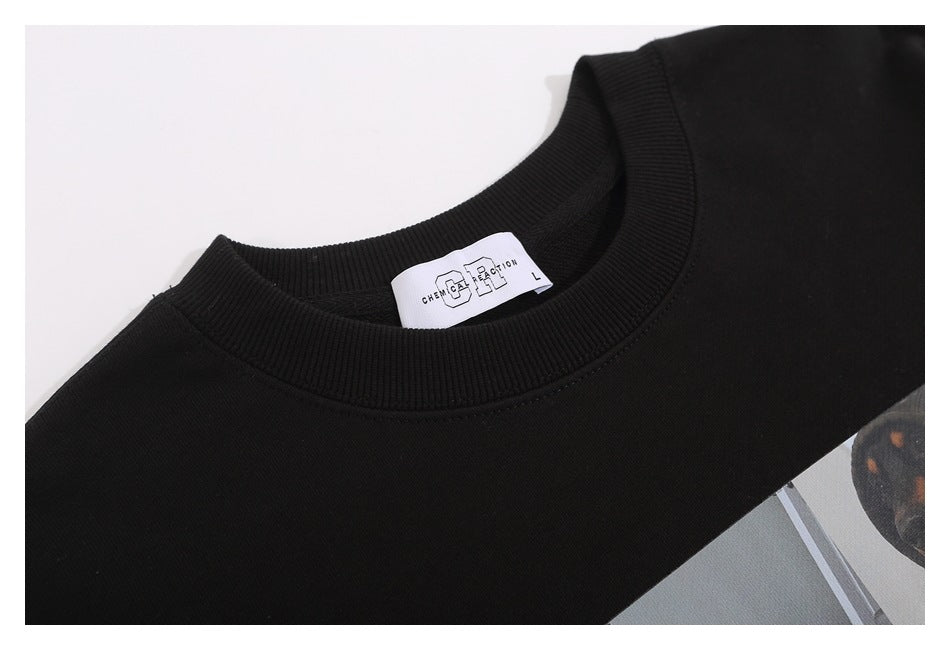Close-up of a black sweatshirt's ribbed neckline, white size label, and part of its printed graphic.