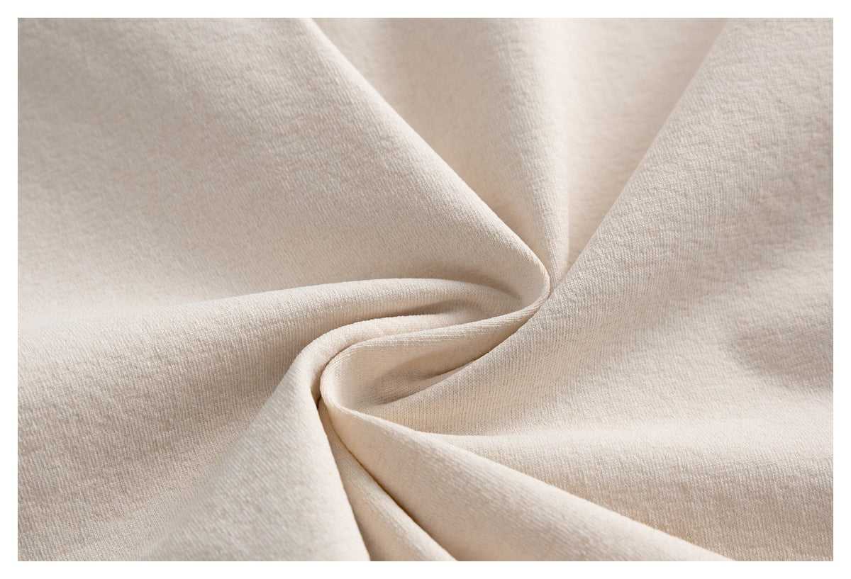 Extreme close-up of softly folded beige garment fabric showing its surface texture.