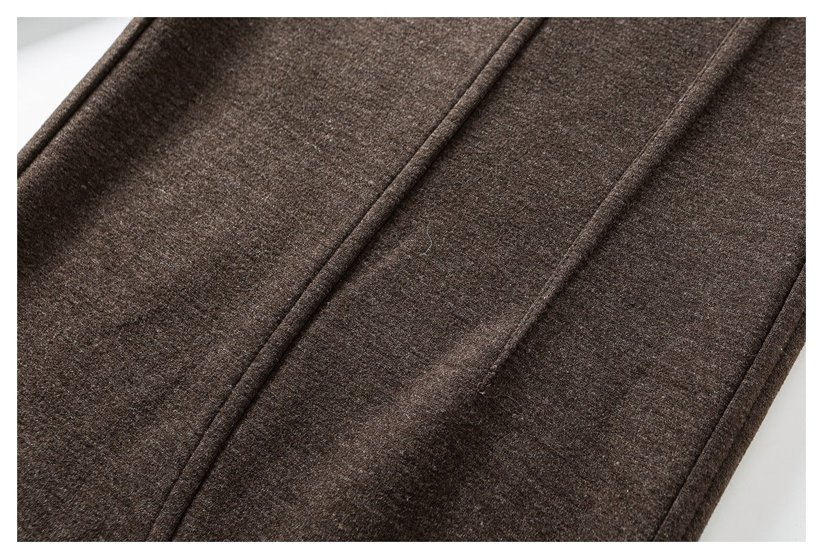 Close-up of brown trouser fabric and parallel stitched seams along a leg.