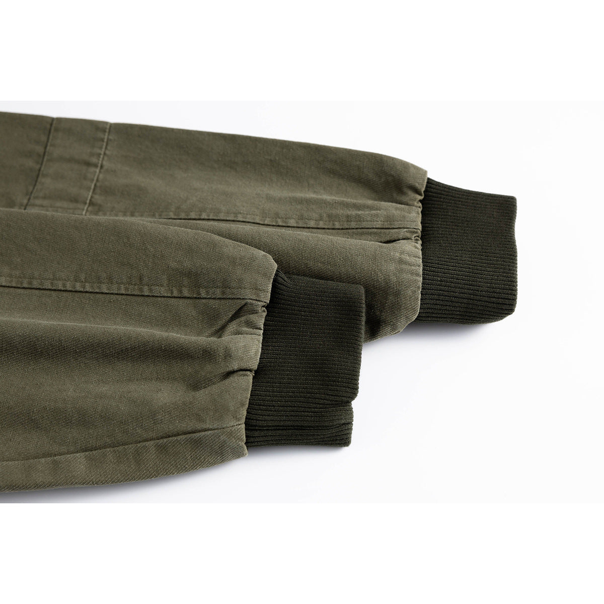 Close-up of an olive jacket’s gathered sleeves and dark ribbed cuffs.