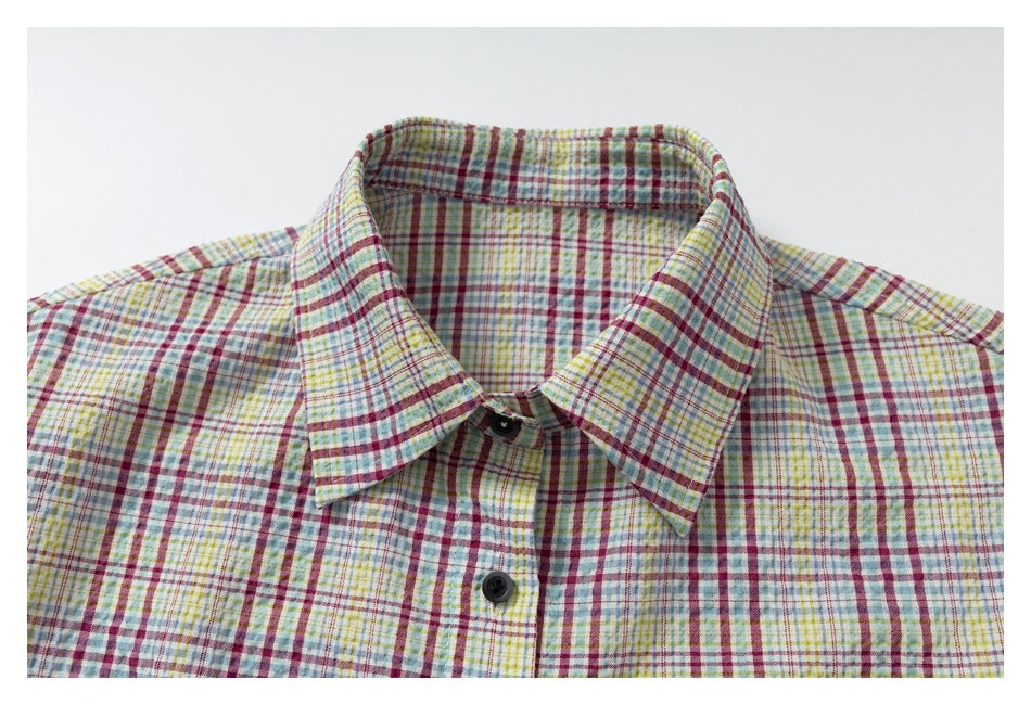 Close-up of the pointed collar and dark buttons on a short-sleeve multicolor plaid shirt.