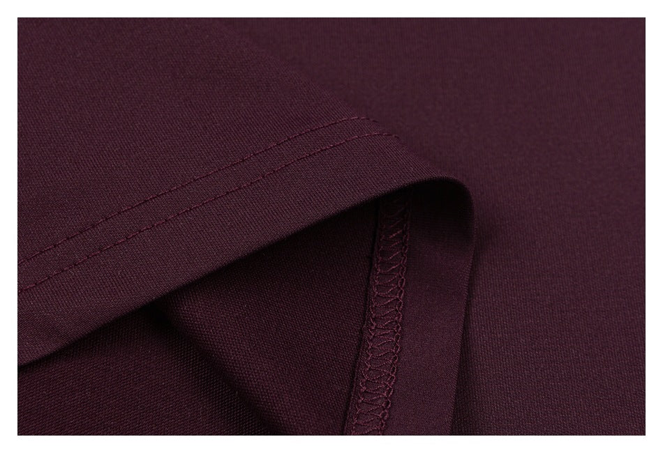 Close-up of the dark burgundy T-shirt's folded hem and overlocked interior seam.