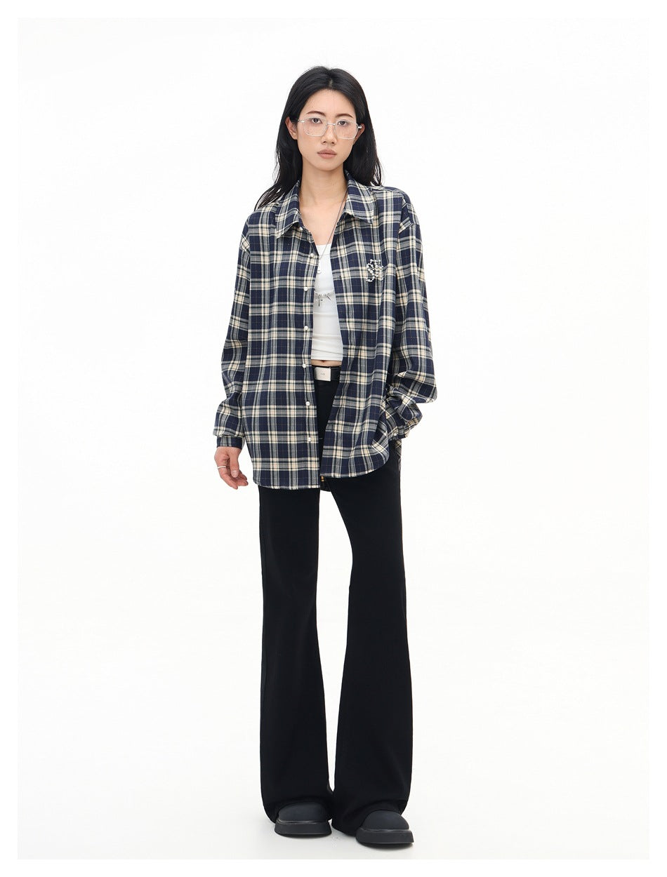Model wearing an open navy plaid shirt over a white cropped top with black flared pants and black shoes