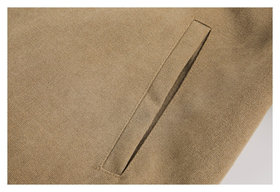 Close-up of a slanted welt pocket on tan textured jacket fabric.