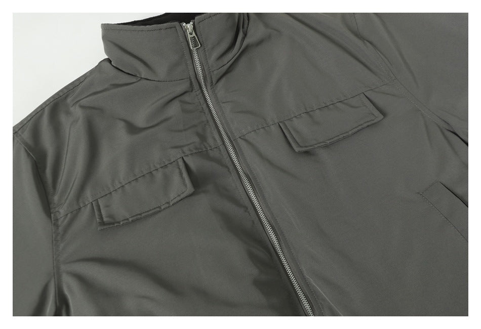 Close-up of the dark gray jacket front, showing a zipper and two flap chest pockets.