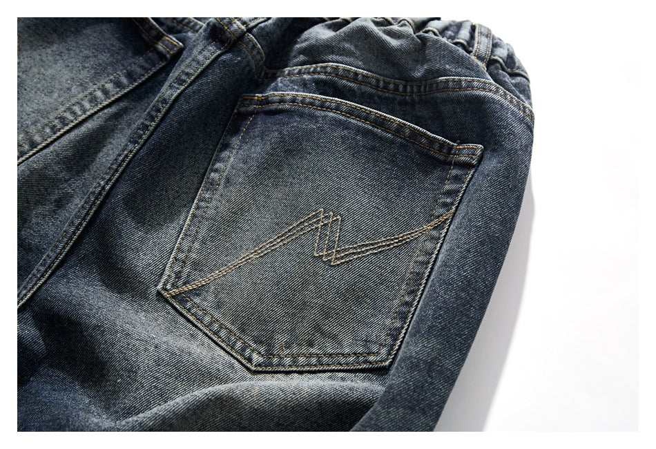 Close-up of a back pocket on dark washed jeans with angular tan stitching.