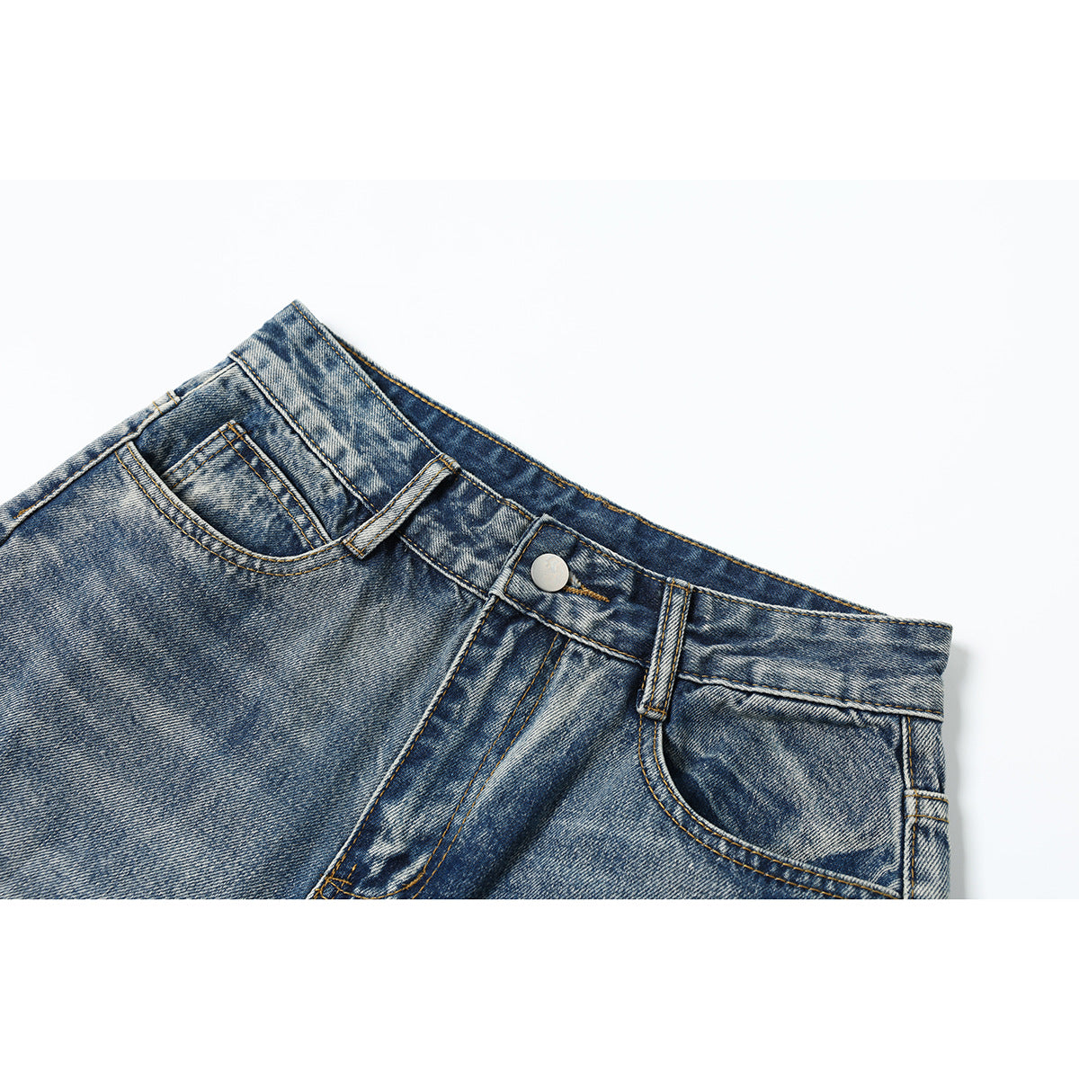 Close-up of the front waistband, button, belt loops and pockets of blue acid-wash jeans.